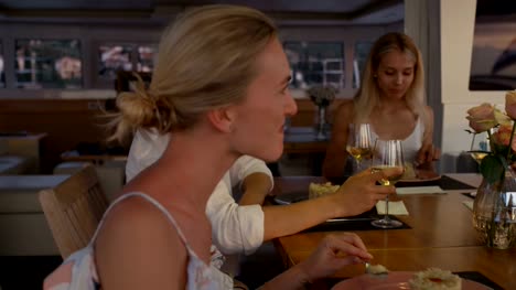 Group-of-Successful-Young-People-Eat-Deserts-on-Yacht.-It's-Evening,-Sea-is-Calm-and-Islands-are-Visible-on-the-Horizon.