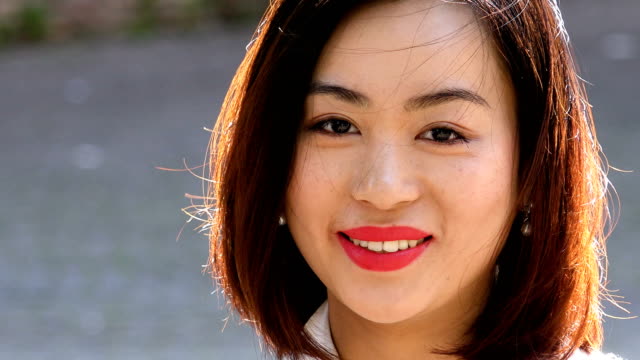 Schöne-junge-asiatische-Frau-törnt-Kopf-und-lächelt-in-die-Kamera-hautnah