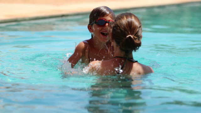 Mother-and-child-playing-at-the-swimming-in-pool-in-4k.-Mom-throwing-child-inside-water-in-slow-motion