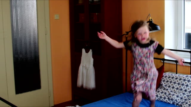 Niedliche-kleine-Mädchen-tanzt-auf-einem-Bett.-Kindheit-Konzept