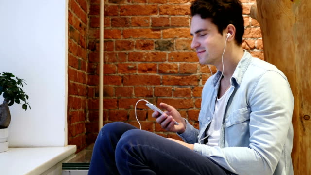 Menschen-hören-Musik-auf-Smartphone-und-tanzen,-sitzt-auf-der-Treppe