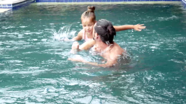 Happy-family,-active-father-with-little-child,-adorable-toddler-daughter,-having-fun-in-swimming-pool.