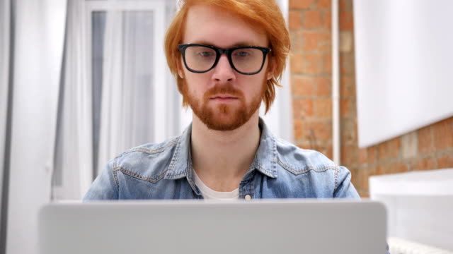 Portrait-of-Smiling-Positive-Redhead-Beard-Man-Working-on-Laptop