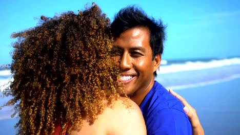Loving-multi-ethnic-couple-relaxing-on-beach-holiday