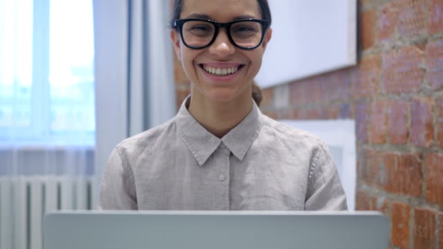 Smiling-Hispanic-Woman-Sitting-and-Working-on-Laptop