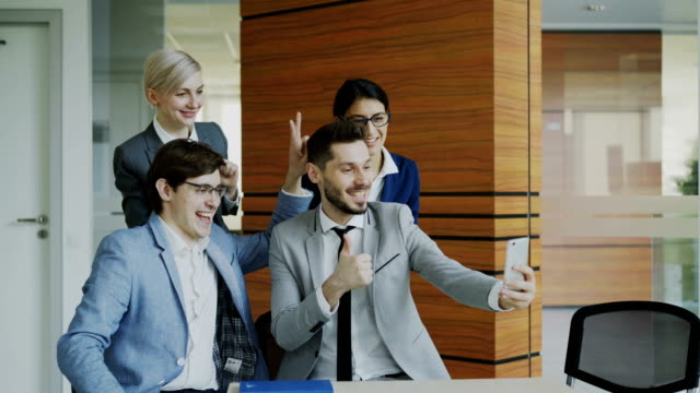 Glücklich-Geschäftsteam-Selfie-Porträt-auf-Smartphone-Kamera-und-posieren-für-Gruppenfoto-während-der-Sitzung-im-modernen-Büro