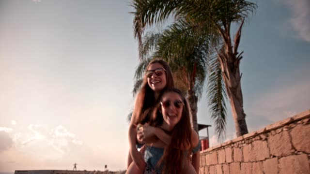 Teenage-girls-having-fun-with-piggyback-ride-on-summer-vacations