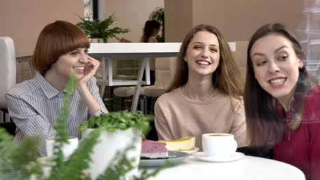 Drei-junge-Mädchen-sitzen-in-Cafés,-Lächeln,-lachen,-Freunde,-Firma,-Klatsch,-Dialog,-Diskussion.-Freundinnen-in-der-Café-Konzept.-Tee-trinken,-Kuchen-essen.-60fps