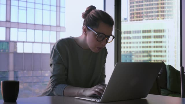Geschäftsfrau-in-Hipster-Gläser-startet-am-Laptop-arbeiten.-Weiblich-ist-Computer-im-Büro-verwenden,-lächelnd-und-Schreiben-auf-einer-Tastatur
