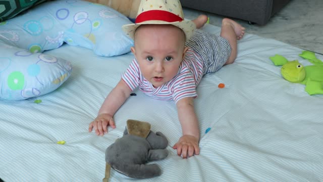 Süße-5-Monate-altes-Baby-Boy-mit-seinem-Strohhut-auf-eine-Spielmatte