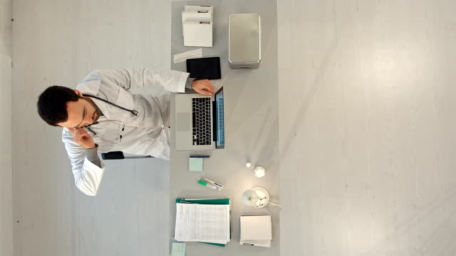 Doctor-with-a-cellphone-and-laptop-computer.-Top-view