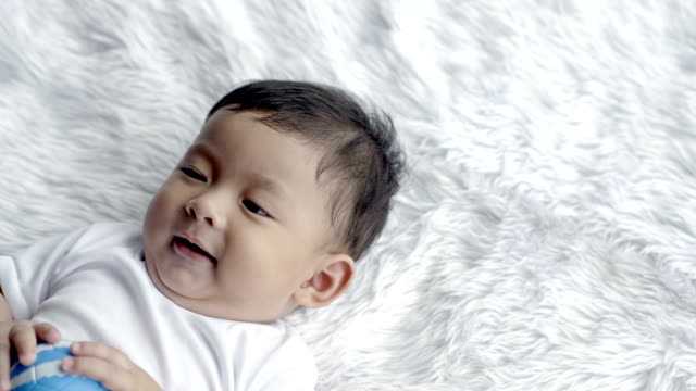 Baby-Boy-Asien-7-Monate-alt-ein-süßes-Lächeln-liegend-auf-einer-Decke.