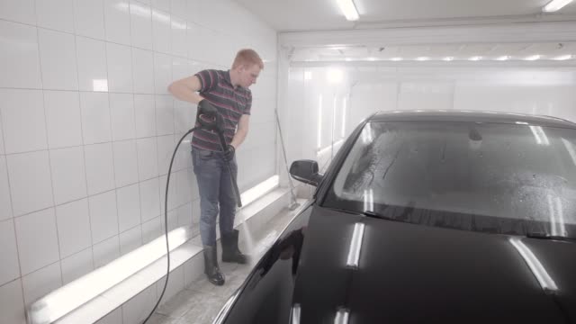 Faceless-person-watering-wheel-in-car-wash