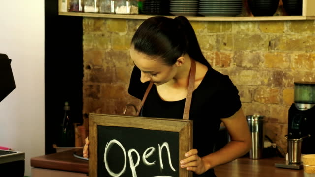 A-coffee-shop-worker-holds-a-Open-sign.