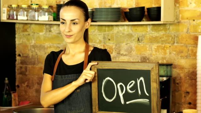 Ein-Coffee-Shop-Arbeiter-hält-ein-Schild-\"geöffnet\".