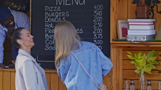 Two-girls-choosing-snack-by-food-booth-menu