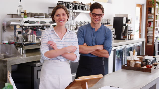 Young-coffee-shop-owners-behind-counter-with-arms-crossed