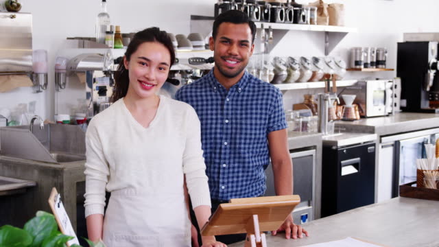 Young-mixed-race-couple-coffee-shop-owners-looking-to-camera