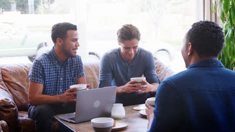 Young-adult-men-drinking-coffee-and-talking-at-a-coffee-shop