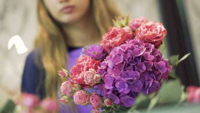 Junge-Frau-Florist-schnüffeln-einen-schönen-Blumenstrauß.-Hübsches-Mädchen-hält-einen-Blumenstrauß-im-Blumenladen.-Blumenstrauß-im-Mittelpunkt.
