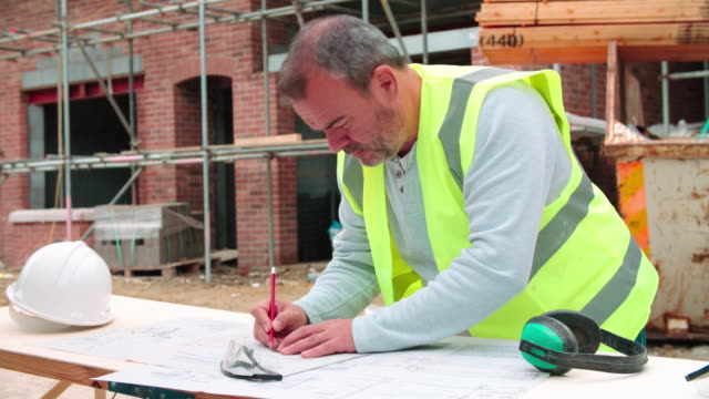 Construction-Worker-Checking-Plans-On-Building-Site