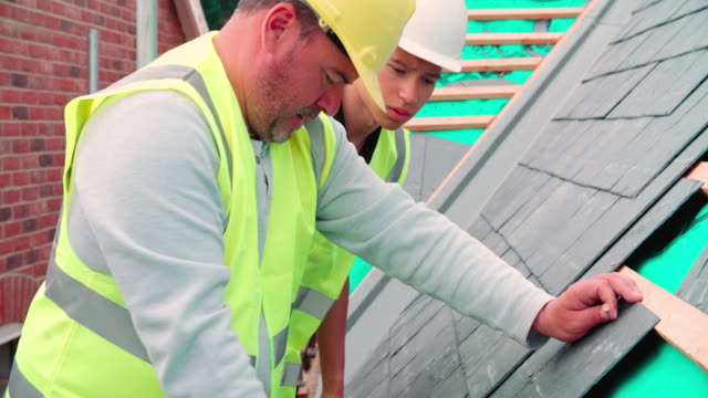Construction-Worker-With-Apprentice-Laying-Slate-Tiles