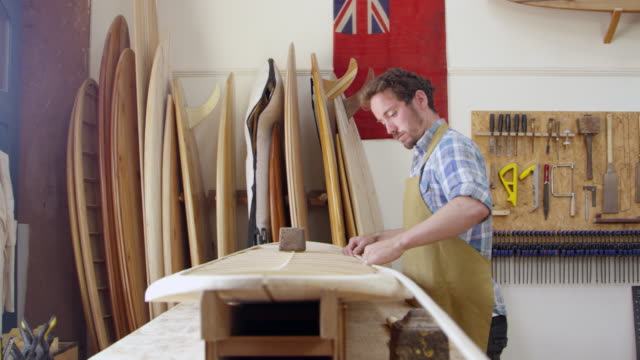 Hombre-construyendo-tabla-de-surf-personalizada-en-el-taller-filmado-en-la-cámara-roja
