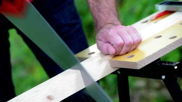 Carpenter-sawing-a-wooden-square-with-a-wood-saw