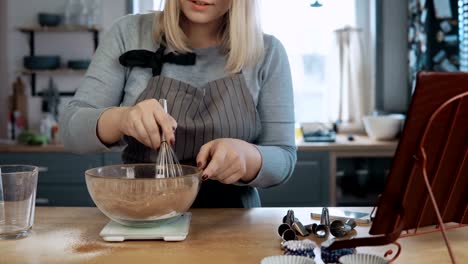 Young-beautiful-woman-standing-on-the-kitchen-and-mixing-ingredients-in-bowl-with-nimbus,-cooking-the-desserts