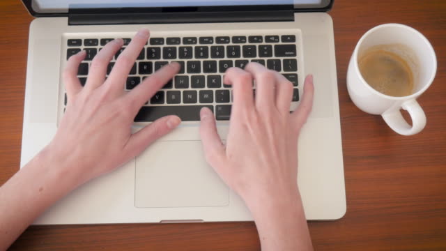 Frau-Typen-auf-einem-Laptop-Computer-an-einem-hölzernen-Schreibtisch