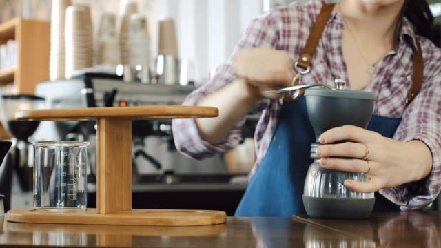 Barista-using-hand-held-coffee-grinder