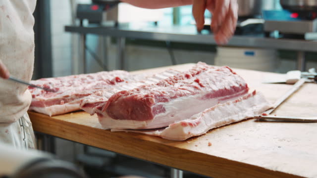 Mid-section-of-butchers-preparing-cuts-of-meat