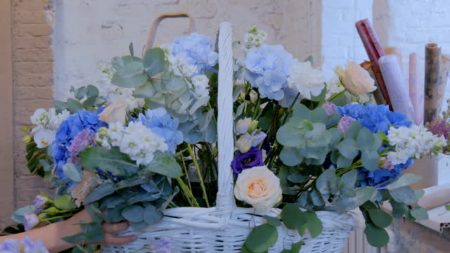 Floristas-de-dos-mujeres-haciendo-la-gran-cesta-de-flores-con-flores-en-la-tienda-de-la-flor