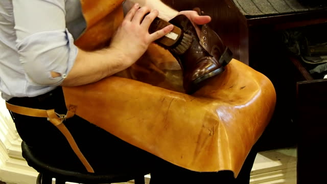 Shoe-shiner-polishes-the-boots-of-brown-leather-with-a-special-brush