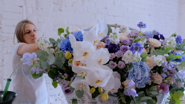 Zwei-Frauen-Floristen-machen-große-Blumenkorb-mit-Blumen-im-Blumenladen