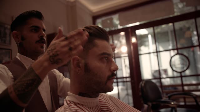 Barber-styling-man's-hair-after-haircut-in-old-fashioned-barber-shop