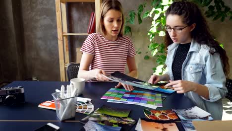 Pair-of-young-designers-are-choosing-photos-for-important-project.-They-are-putting-pictures-on-table-and-discussing-them.-Busy-day-in-design-company-concept.