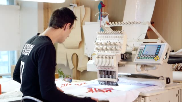 Young-man-is-embroidering-pattern-on-computerized-machine
