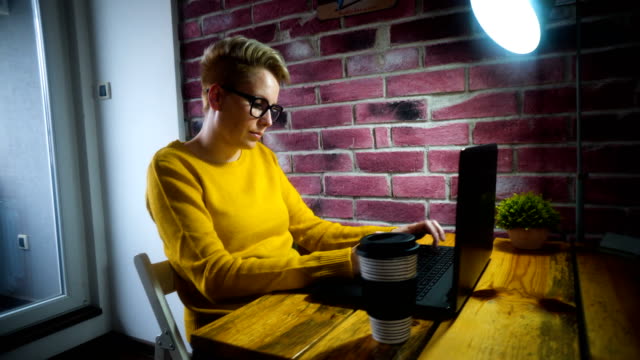 Attractive-young-woman-working-at-the-desk-with-a-laptop-in-home-office.