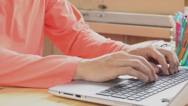 Empresario-de-camiseta-manga-larga-naranja-escribir-portátil-en-oficina-en-casa.-Trabajo-y-la-comunicación-por-Internet