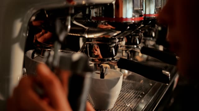 Close-up-of-barista-steaming-milk-at-coffee-machine-in-café