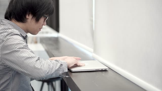 Junge-asiatische-Geschäftsmann-mit-Laptop-Computer-im-Arbeitsraum.-Männliche-Hand-auf-Laptop-Tastatur-für-Login-Kennwort-einzugeben.-Freiberuflicher-Lebensstil-im-digitalen-Zeitalter-Konzept.