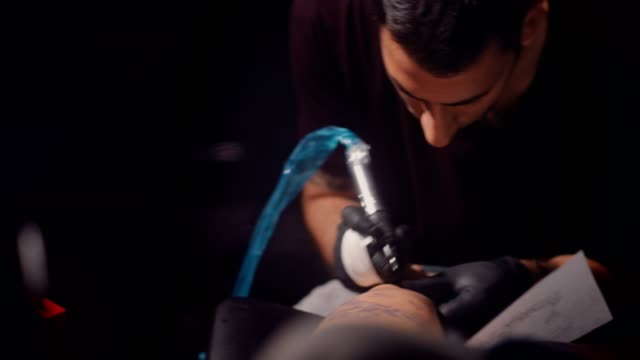 Hipster-tattoo-artist-tattooing-design-with-ink-in-professional-studio