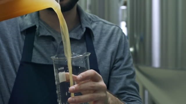 Man-Pouring-Beer-into-Measuring-Jug-at-Brewery