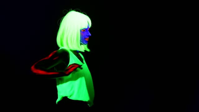 Woman-with-UV-face-paint,-wig,-glowing-clothing-dancing-in-side-way,-Half-body-shot.-Caucasian-woman.-.