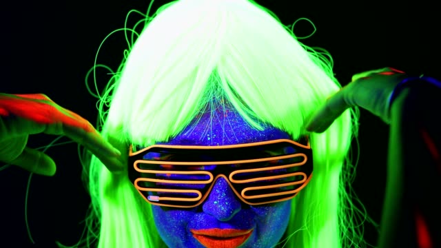 Mujer-con-pintura-UV,-peluca,-gafas-de-rayos-UV,-retrato-de-ropa-brillante,-cara-cerca-de-hacen-para-arriba.-Mujer-caucásica.-.