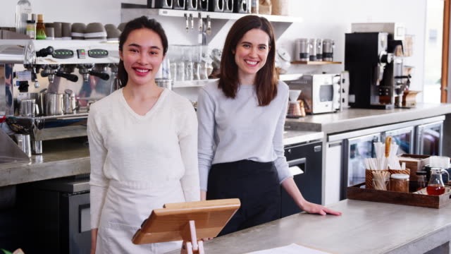 Zwei-weibliche-Unternehmer-hinter-der-Theke-in-ihrem-café