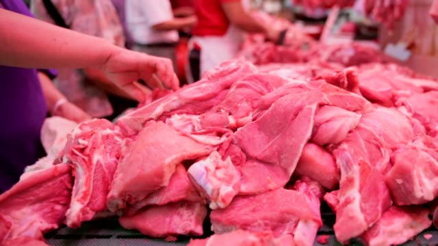 close-up-of-hands-picking-up-pieces-of-raw-meat-from-a-market-pile