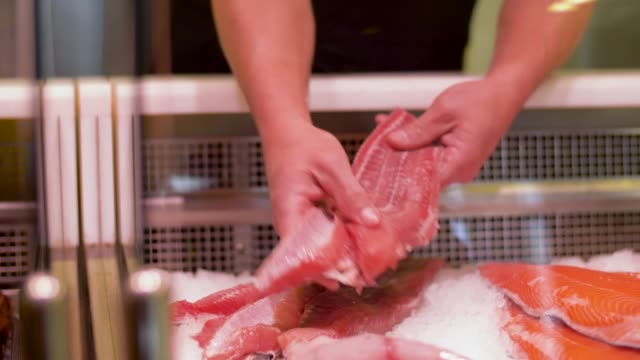 male-seller-putting-fish-fillet-to-fridge-at-shop