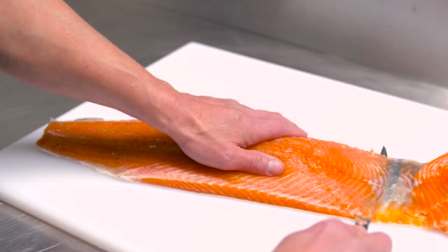male-chef-slicing-smoked-salmon-fillet-at-restaurant-kitchen